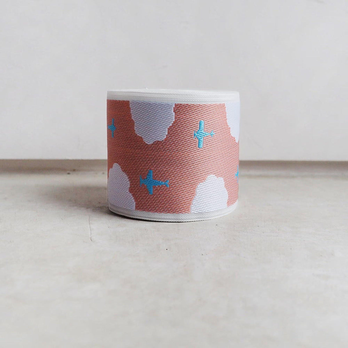 A single object, a circular object with a cloud pattern and blue airplane designs, is placed on a white surface.
