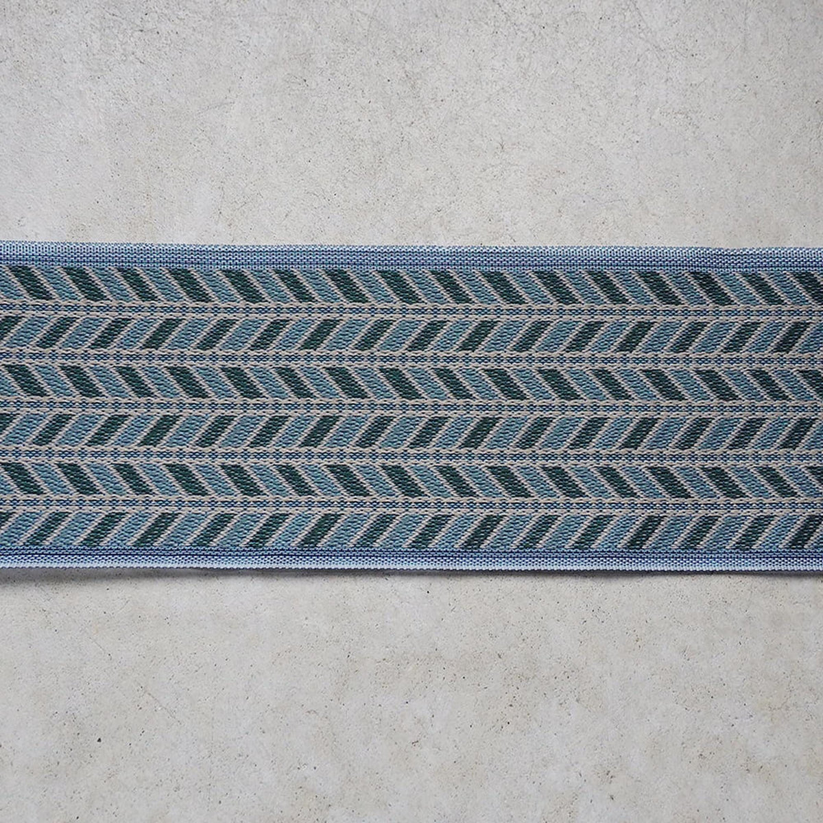 a close-up view of a blue and green patterned fabric or textile, with a repeating geometric design.