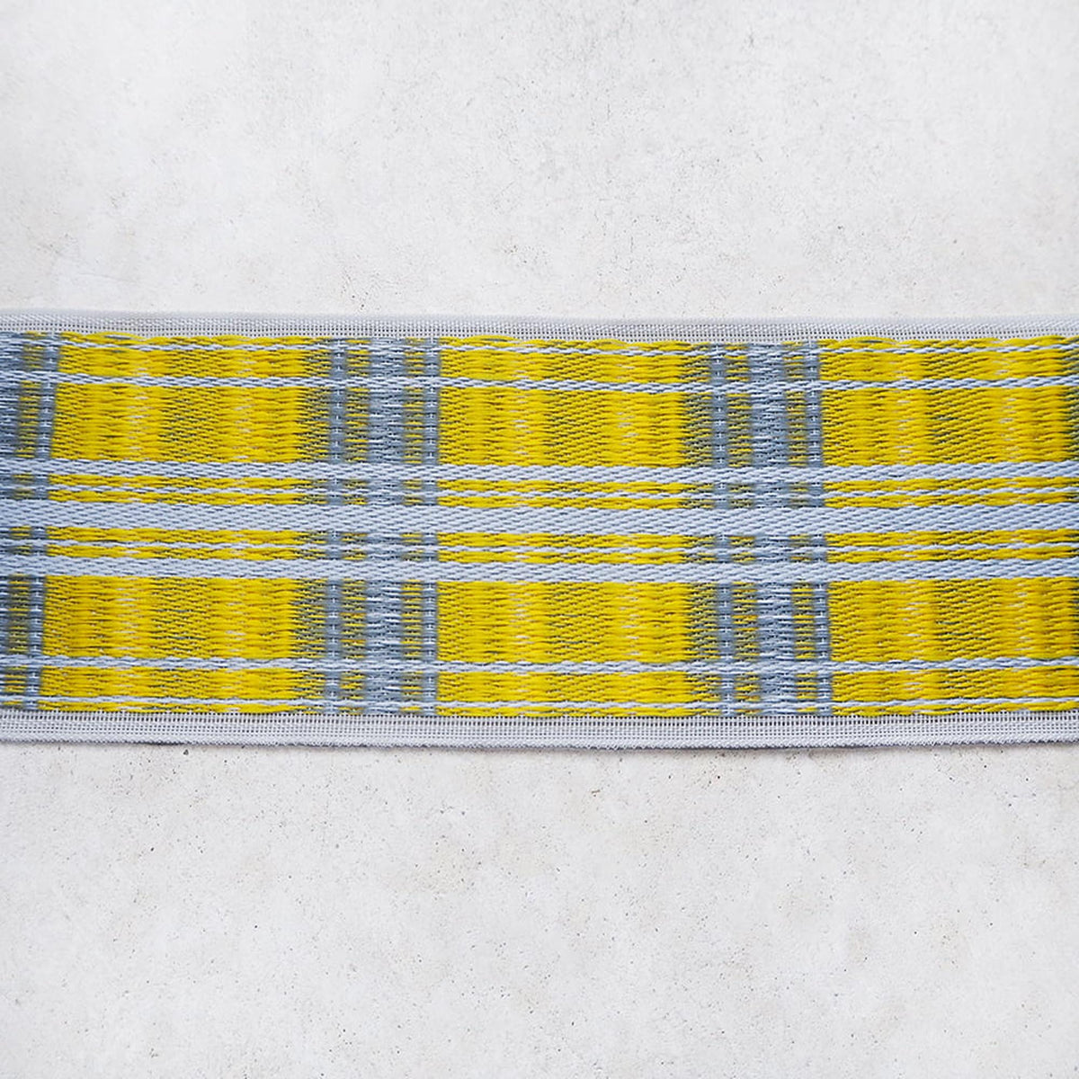 A close-up view of a yellow and blue plaid fabric, with the fabric's pattern and color variations clearly visible.