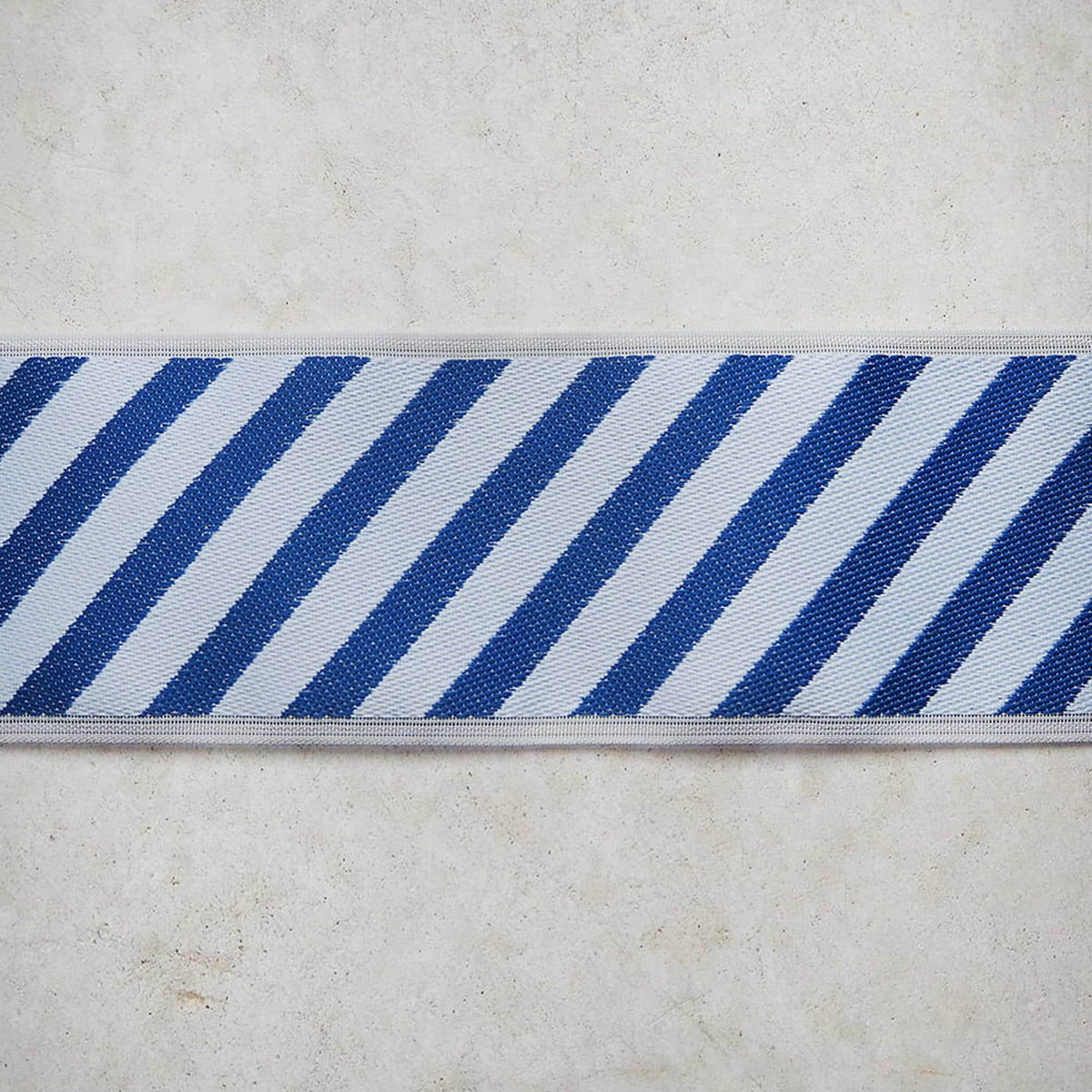 A close-up view of a blue and white striped fabric or ribbon, with the fabric's diagonal stripes clearly visible.
