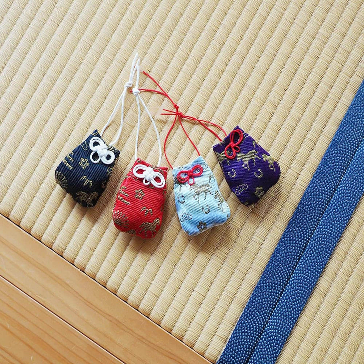 Four colorful bags or pouches with various patterns and designs are arranged on a woven mat.