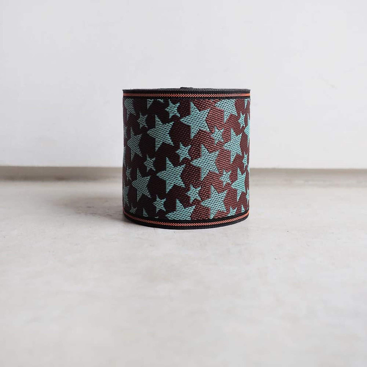 A circular object with a star pattern in shades of blue and brown, placed on a white surface against a plain background.