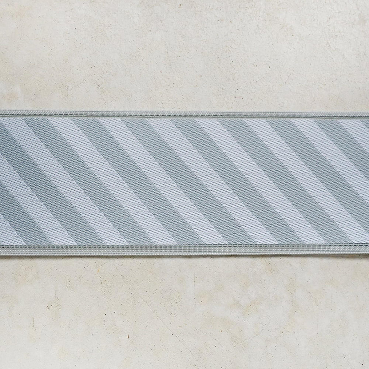 A close-up view of a striped fabric or textile with a diagonal pattern, displayed on a plain background.