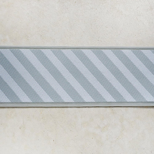 A close-up view of a striped fabric or textile with a diagonal pattern, displayed on a plain background.