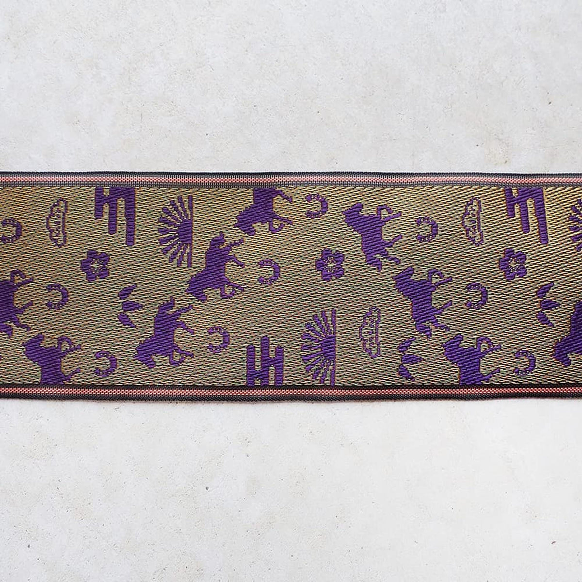 a decorative fabric with a repeating pattern of purple silhouettes of horses and other animals, along with various geometric shapes and designs.