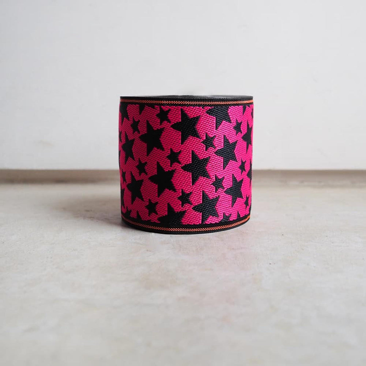 A pink and black star-patterned object is sitting on a white surface.