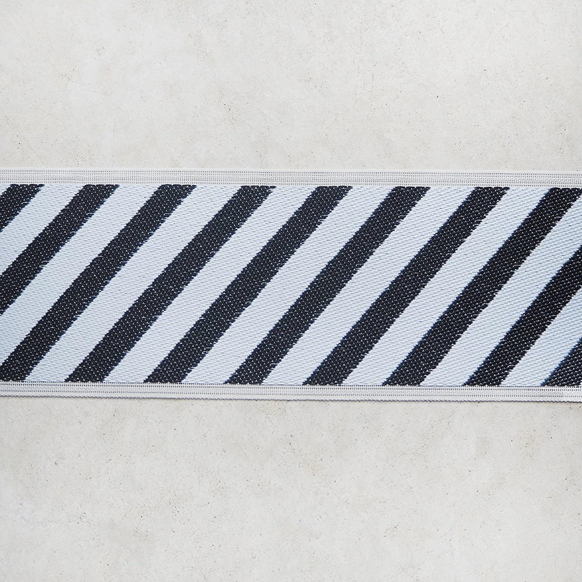 A close-up view of a black and white striped fabric or ribbon, with the diagonal stripes creating a visually striking pattern.