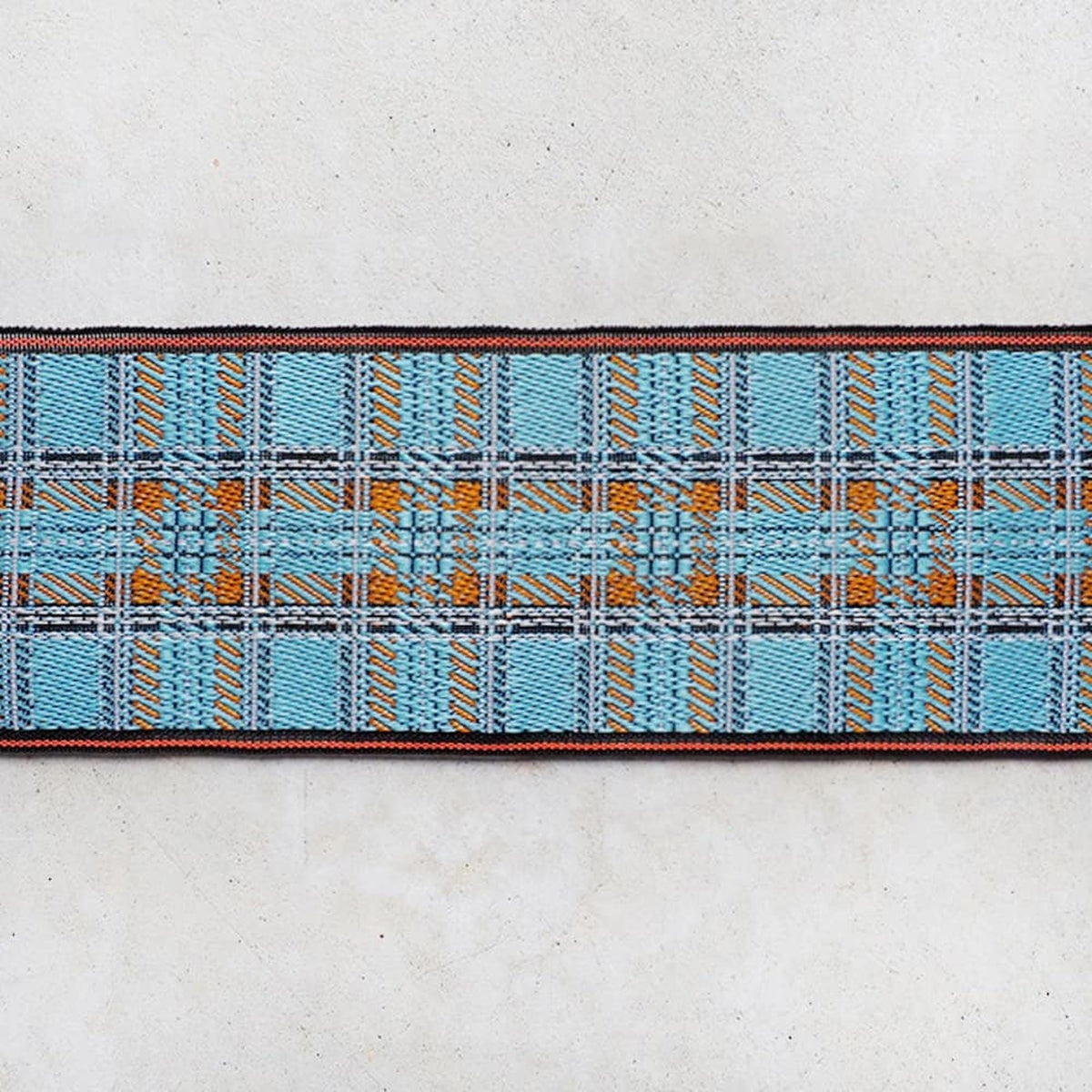 a close-up view of a decorative textile with a blue and orange plaid pattern.