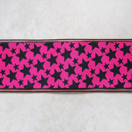 A close-up view of a ribbon with a repeating pattern of pink stars on a black background.