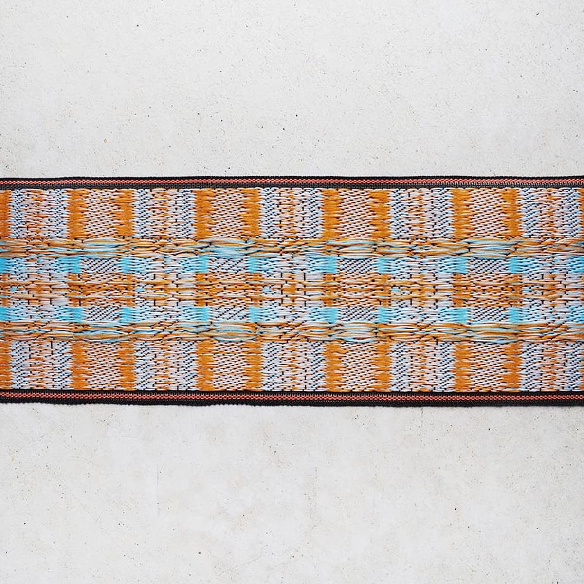 a long, narrow, and colorful textile with a repeating pattern of orange, blue, and white colors.