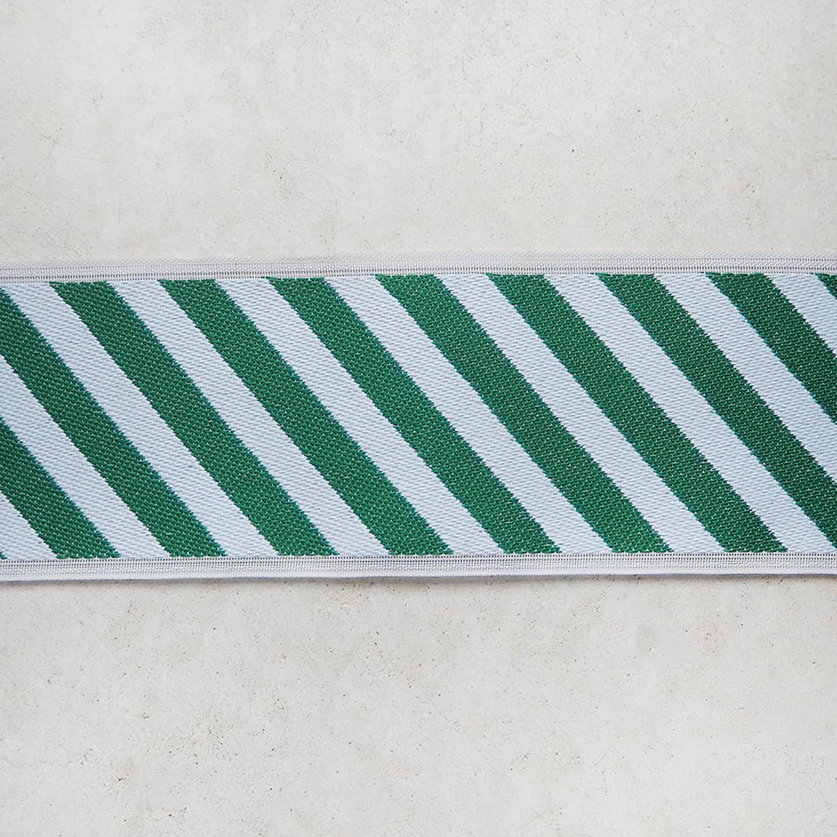 A close-up view of a green and white striped ribbon or band against a plain white background.