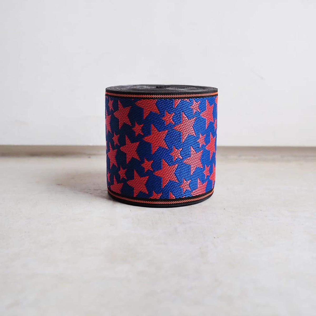 A red and blue star-patterned ribbon is sitting on a white surface against a plain white background.