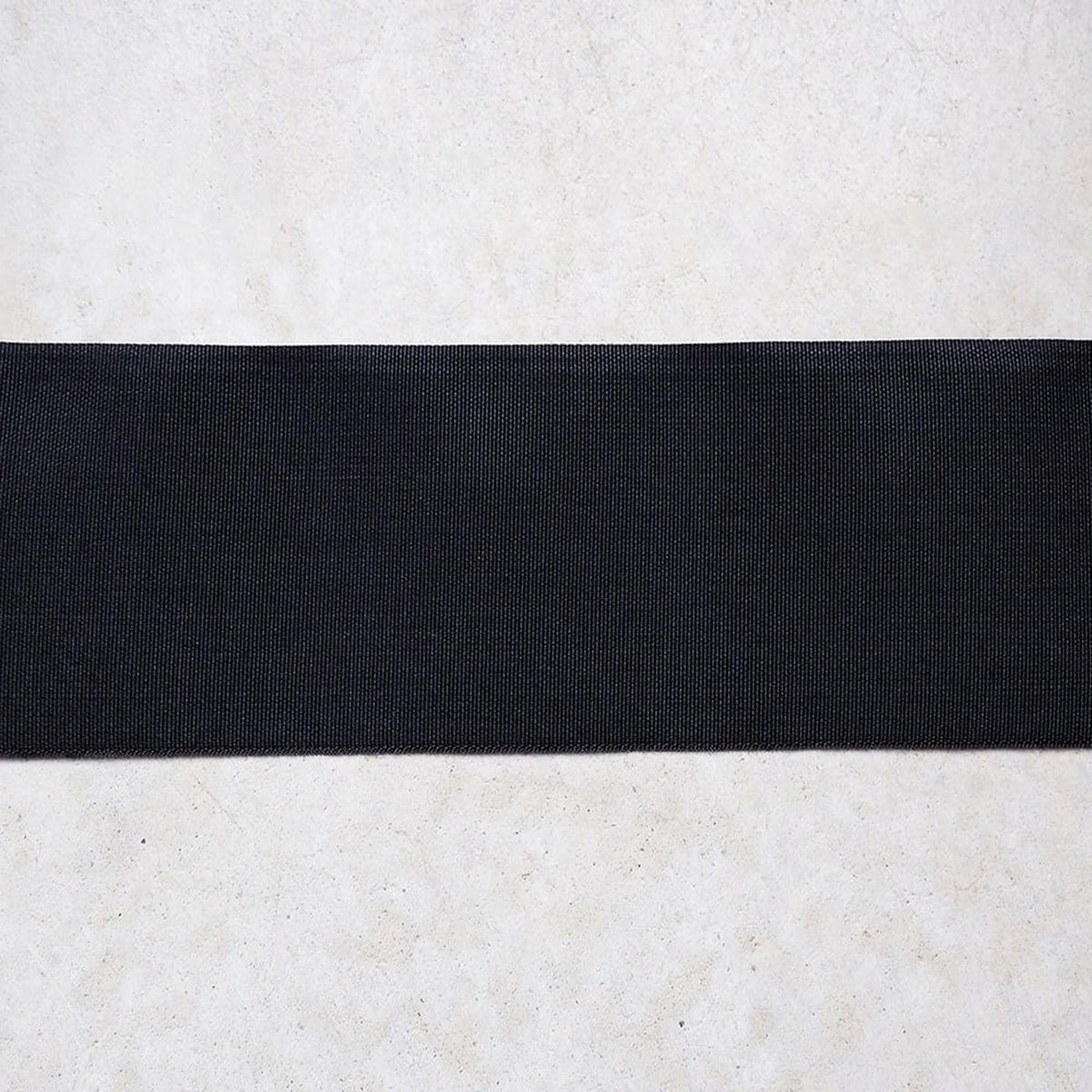 A black rubber band is placed on a white surface.