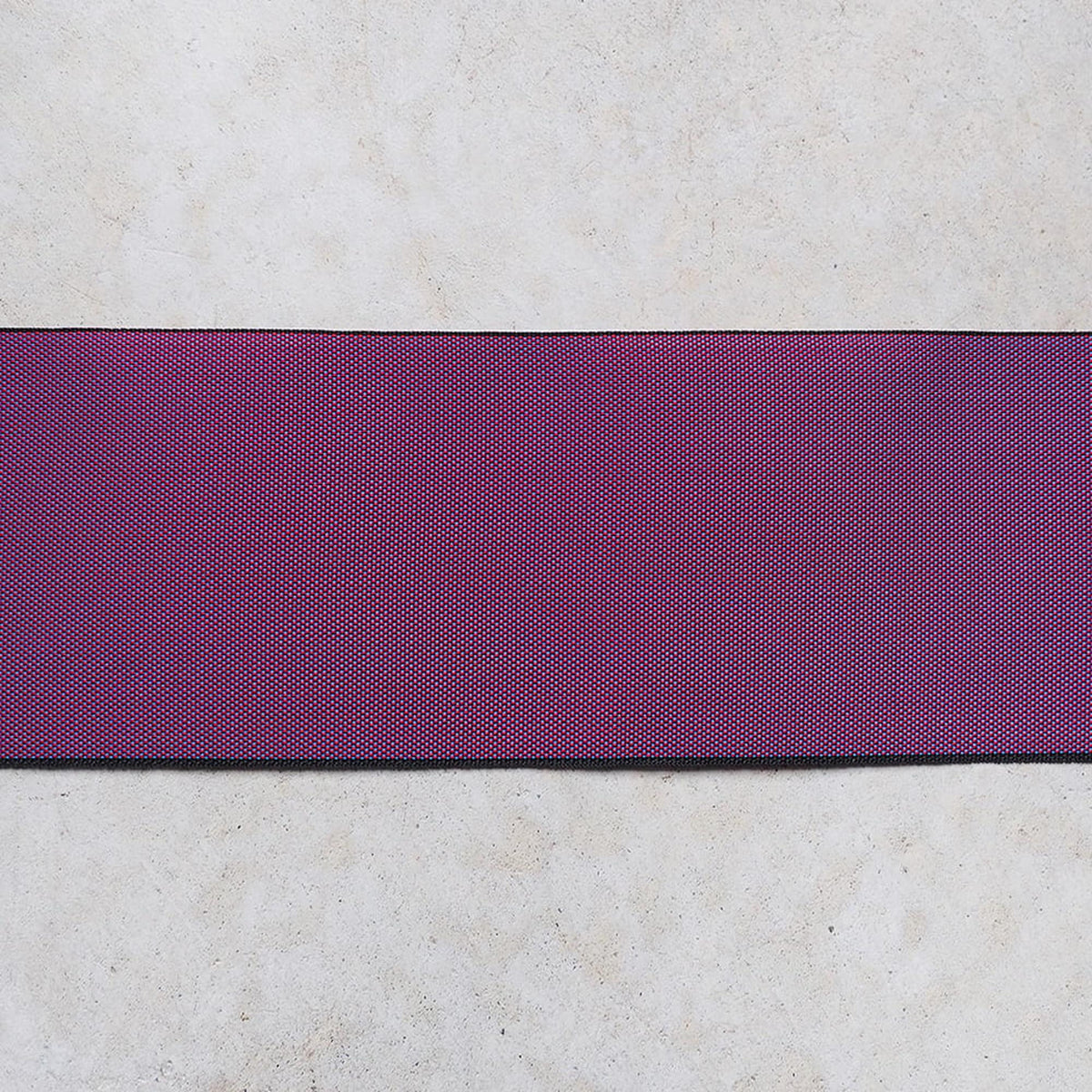 a purple fabric or ribbon with a diagonal pattern, placed on a white surface.