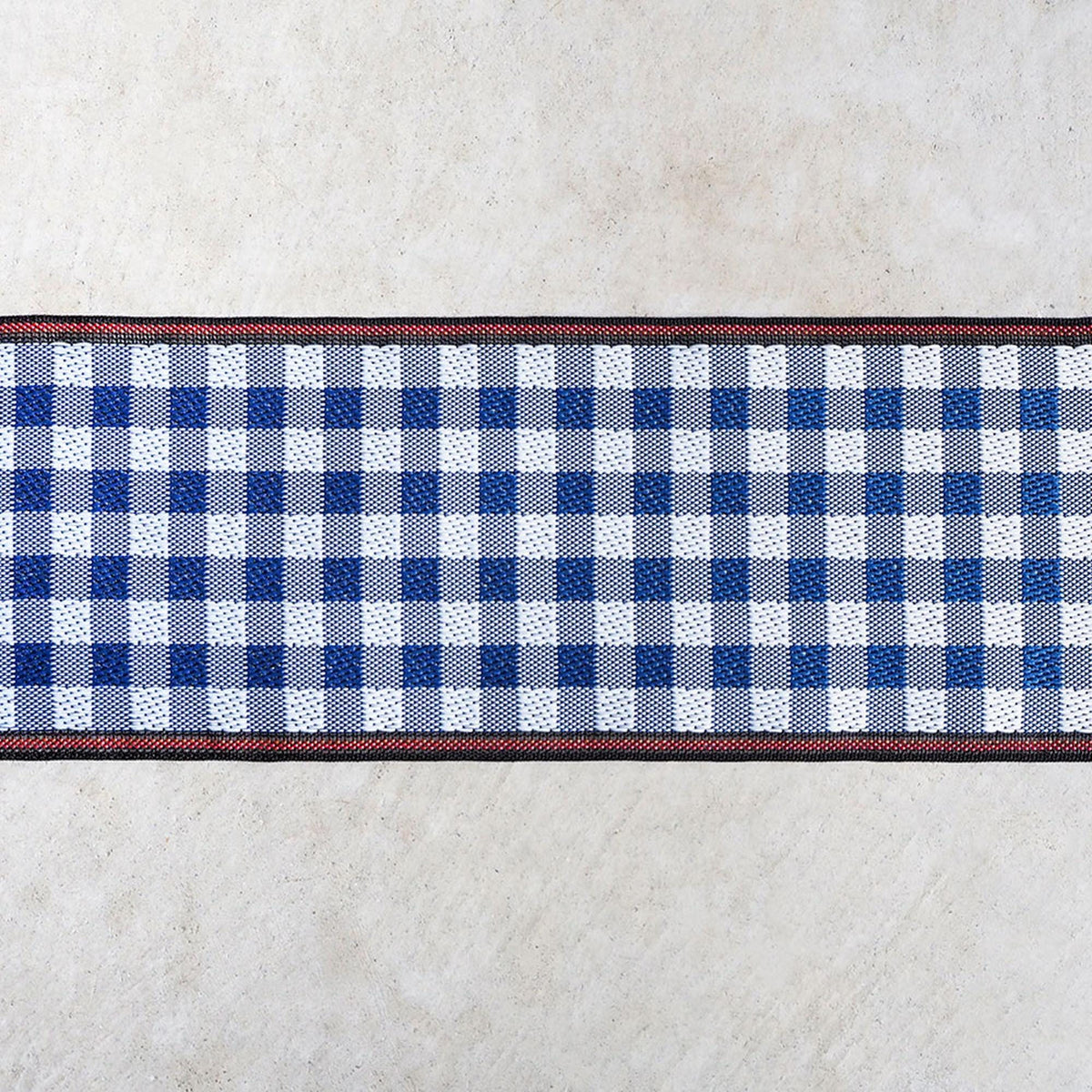 A close-up view of a blue and white checkered pattern on a concrete surface, with a red border around the edge.
