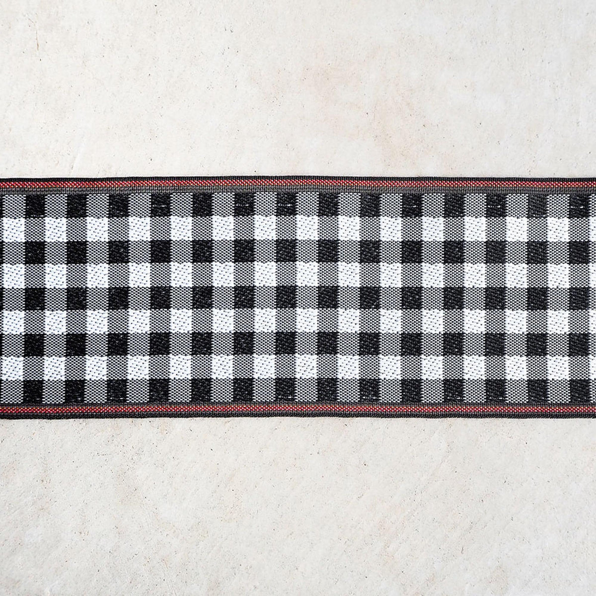 a close-up view of a black and white checkered pattern with a red border, set against a plain white background.