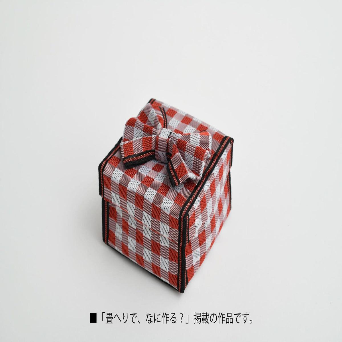A small red and white checkered gift box with a bow, sitting on a plain white background.