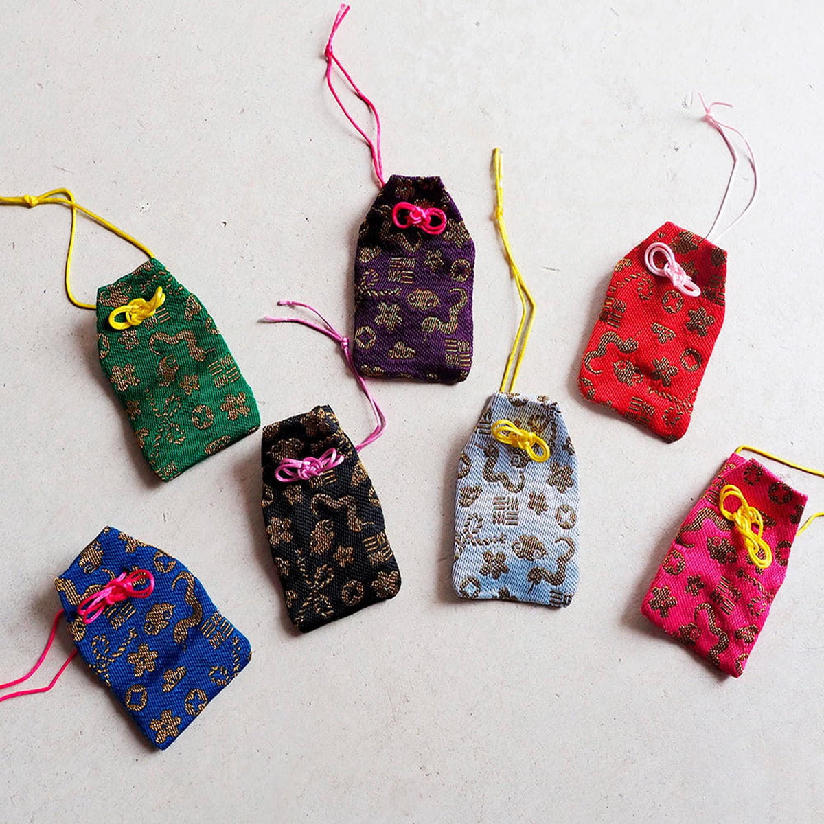 a collection of colorful fabric bags or pouches, each with a unique pattern and color, arranged on a white surface.