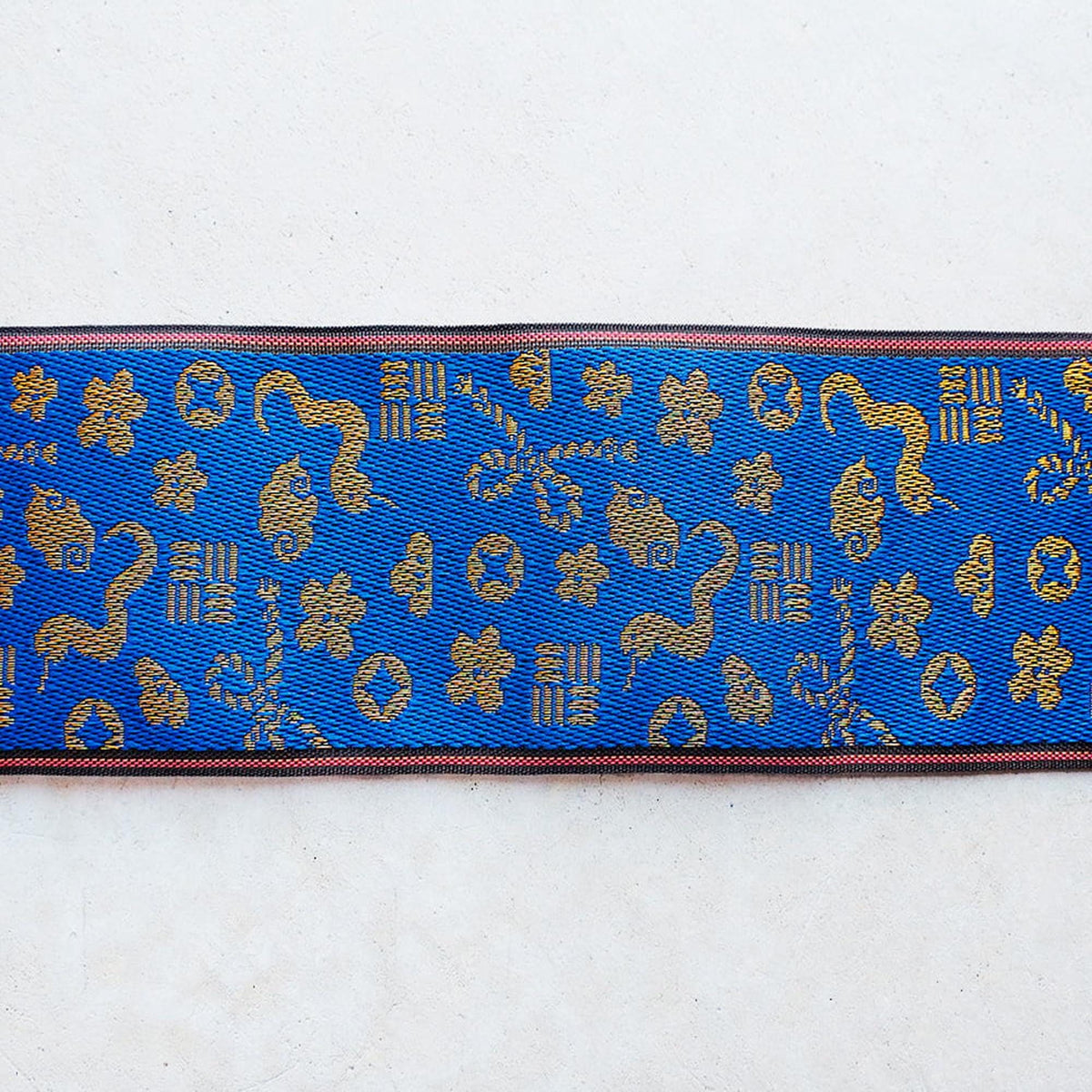 a blue and gold patterned fabric with various shapes and designs, including flowers, leaves, and geometric patterns.