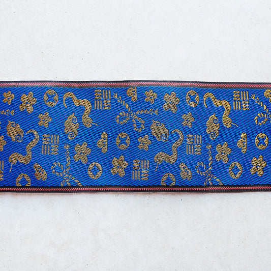 a blue and gold patterned fabric with various shapes and designs, including flowers, leaves, and geometric patterns.