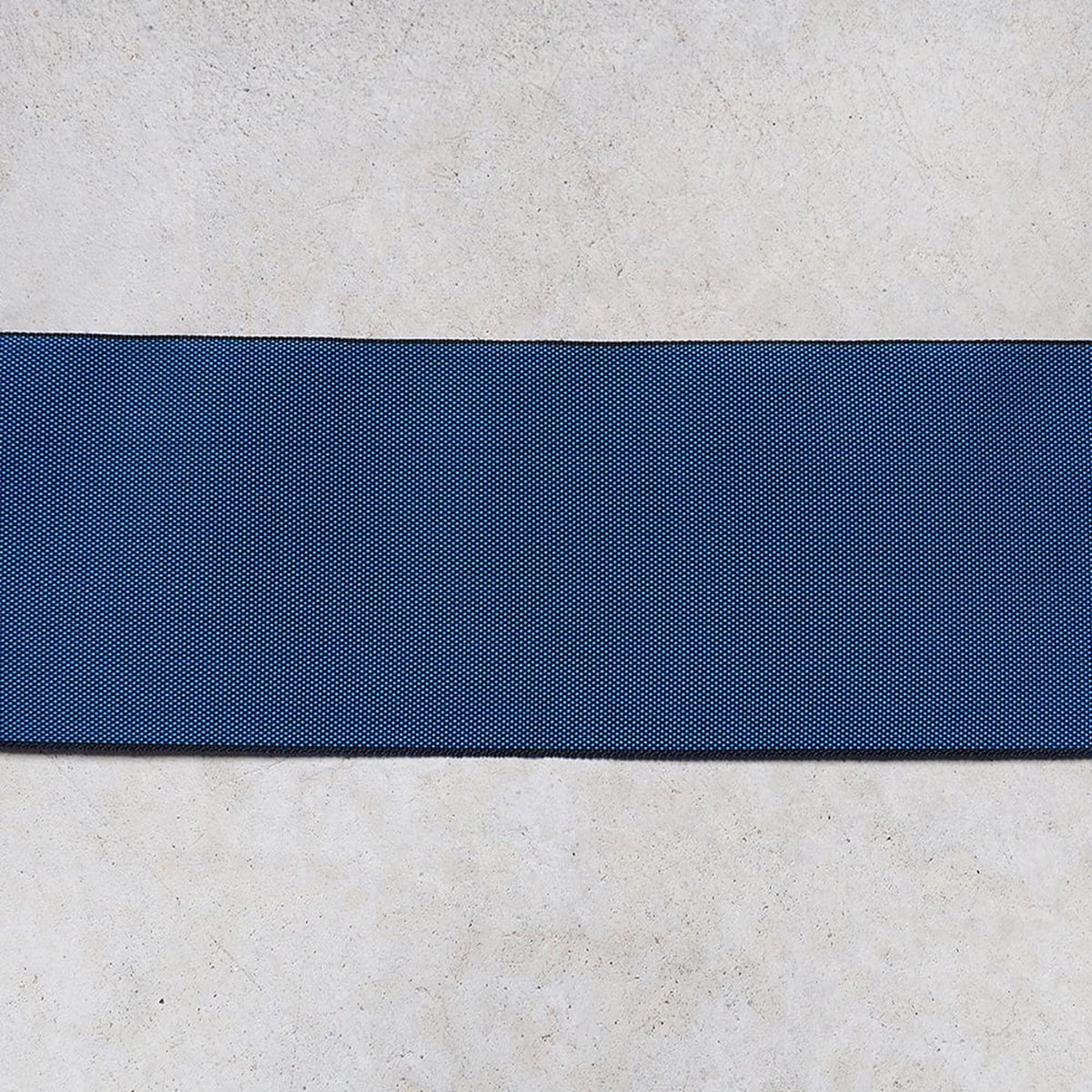 a blue fabric with a diagonal stripe across it, placed on a white surface.