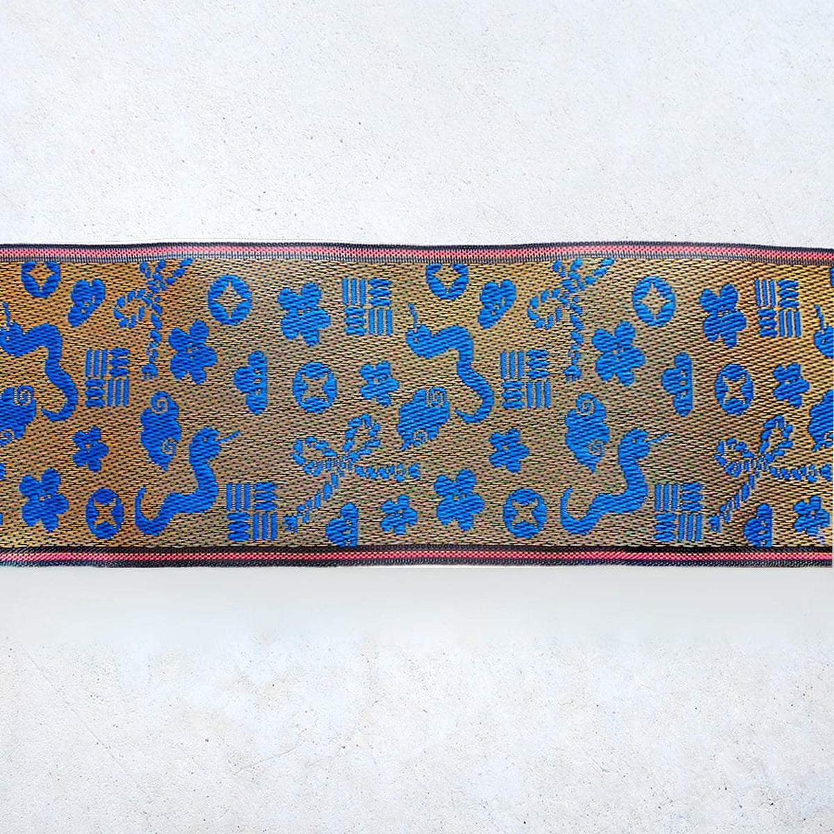 a decorative fabric with a repeating pattern of blue and gold shapes, including flowers, leaves, and geometric designs.