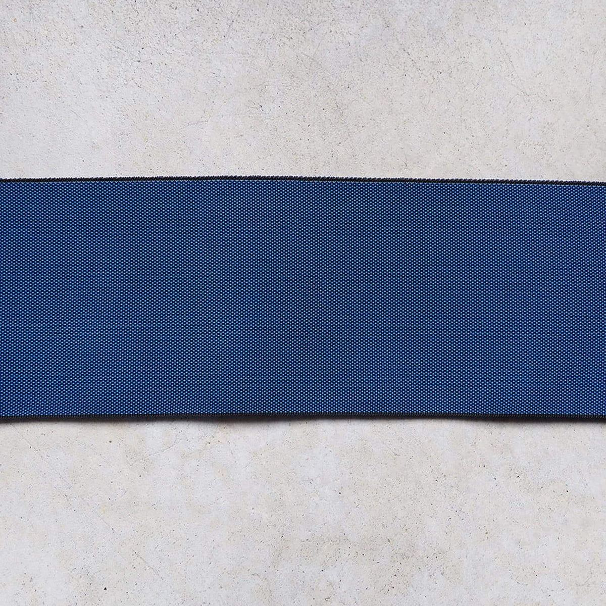 a blue fabric or material with a diagonal stripe across it, placed on a white surface.