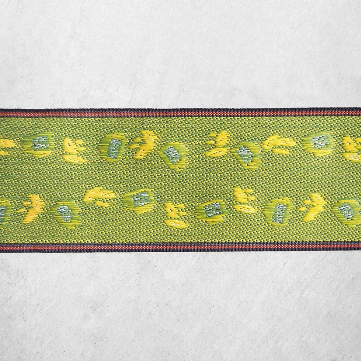 a green and yellow patterned fabric with a repeating design of green and yellow flowers or leaves.