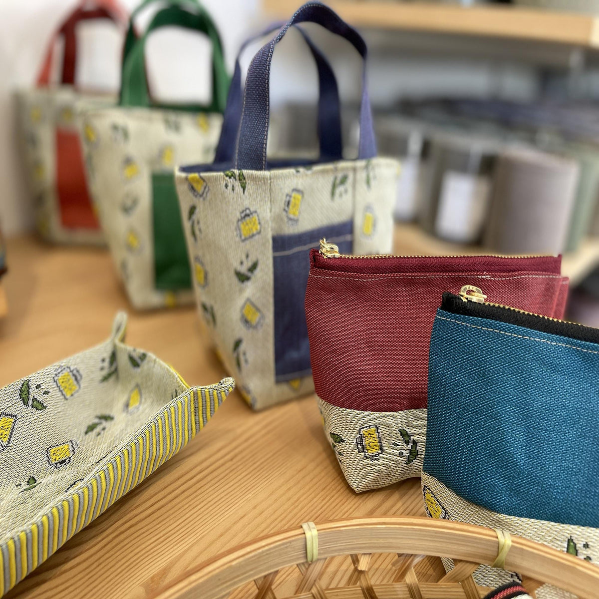 a variety of colorful handbags and small bags arranged on a wooden surface.
