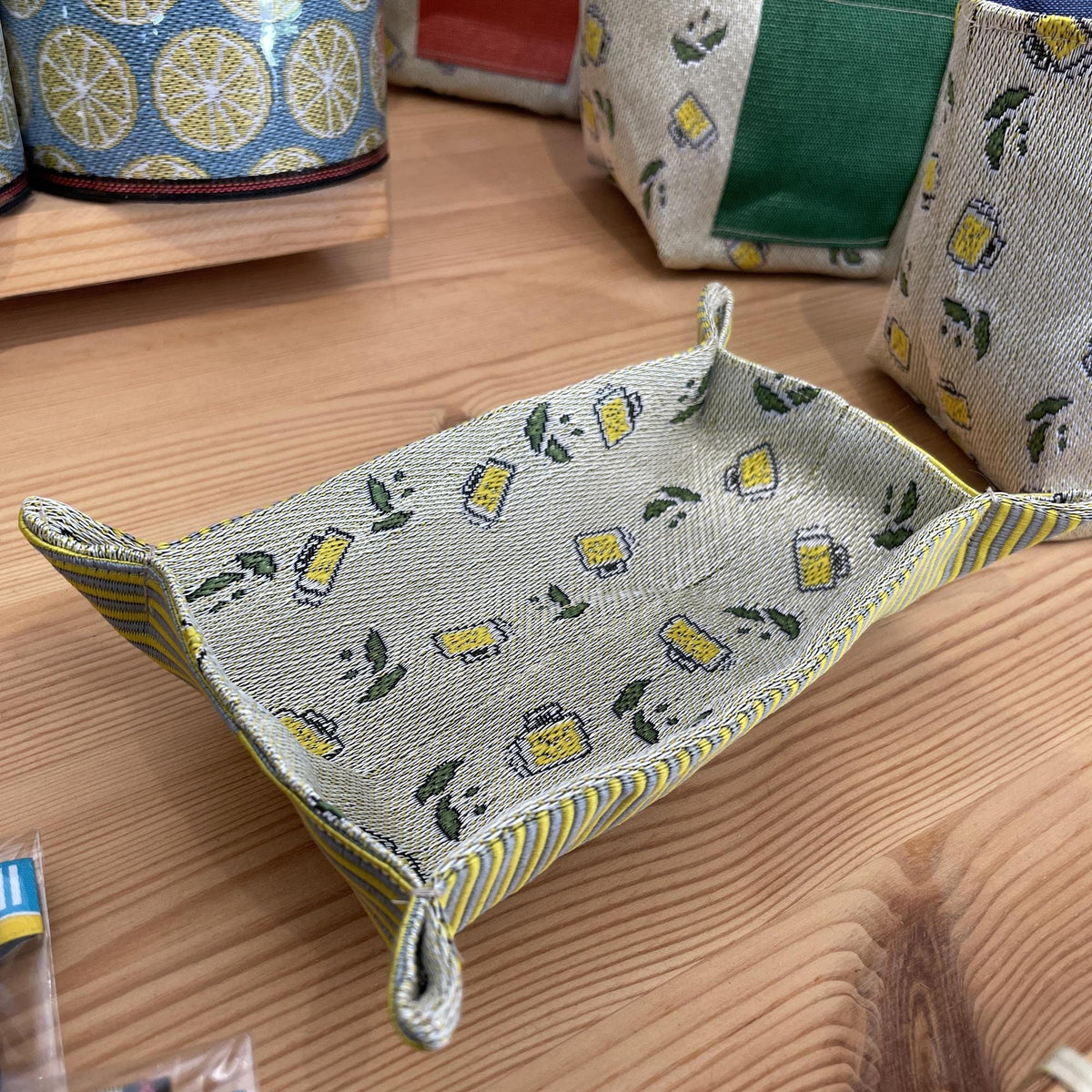 A woven tray with a pattern of yellow and green icons, placed on a wooden surface.