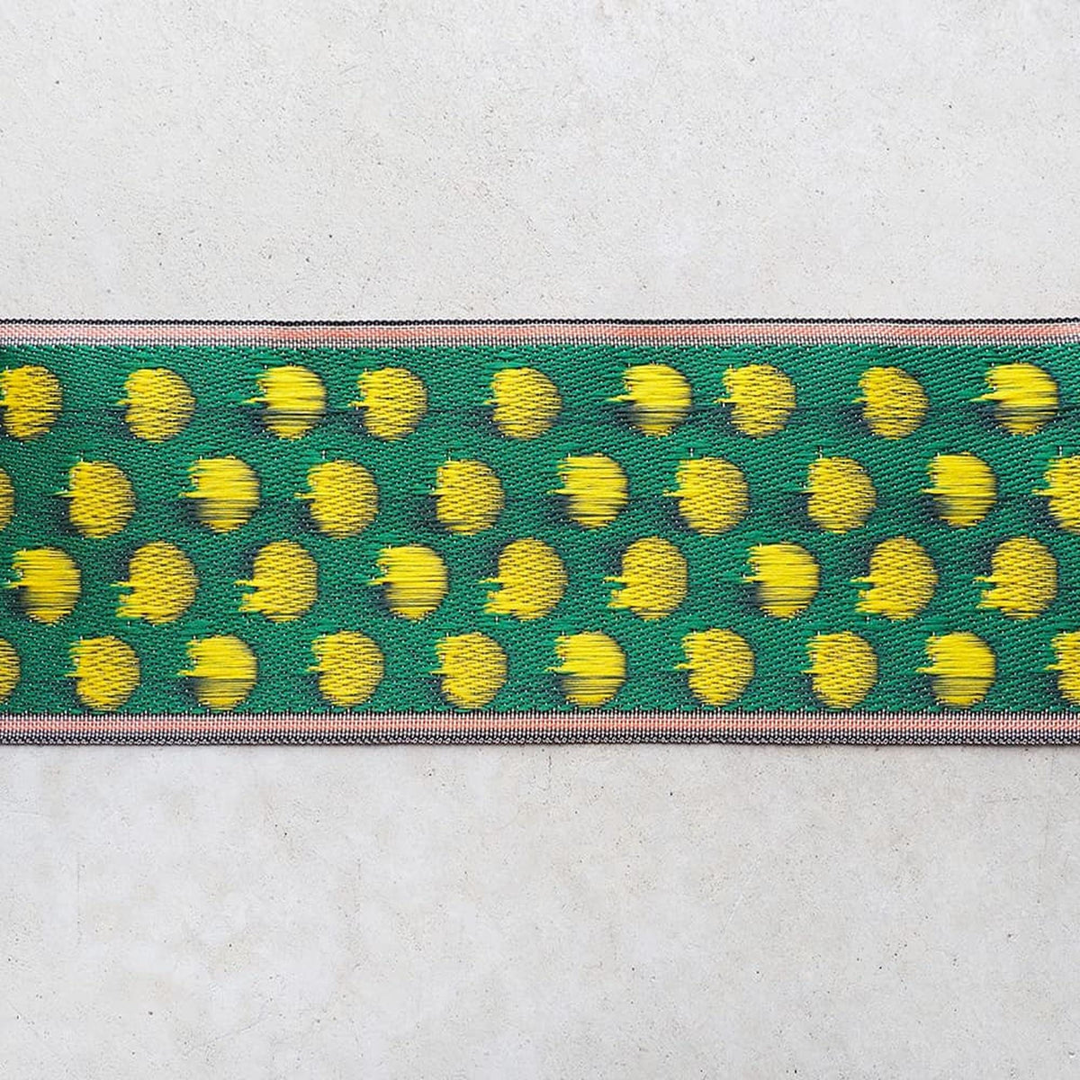 a close-up view of a green and yellow patterned fabric with a repeating design of yellow circles on a green background.
