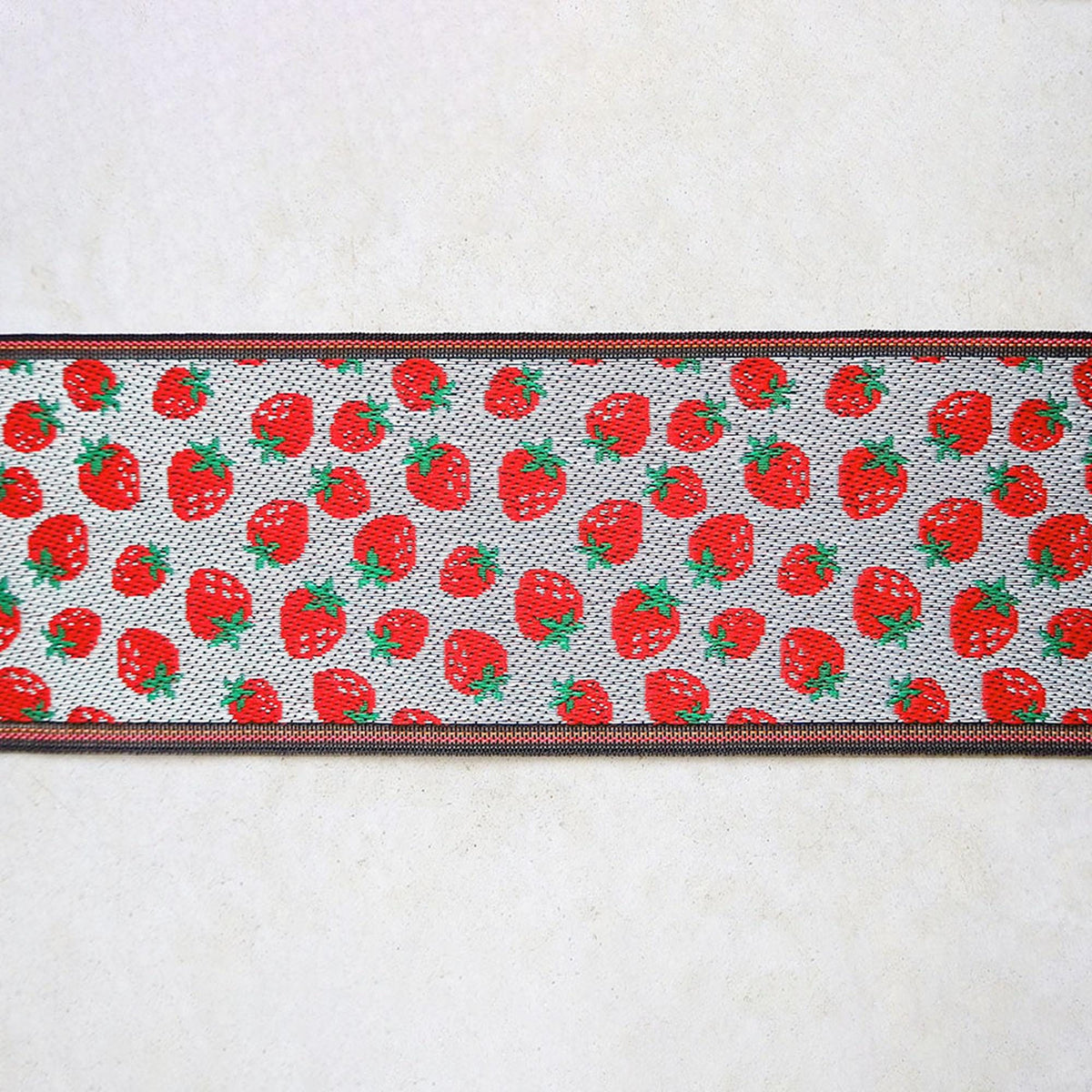 a repeating pattern of red strawberries on a white background, with a black border.
