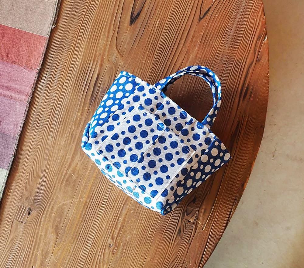 A blue and white polka dot handbag is placed on a wooden surface.