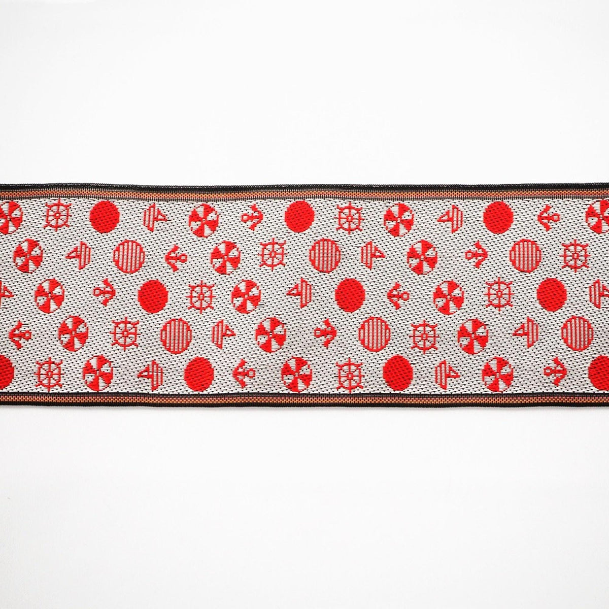 a decorative fabric with a repeating pattern of red circles and white lines.