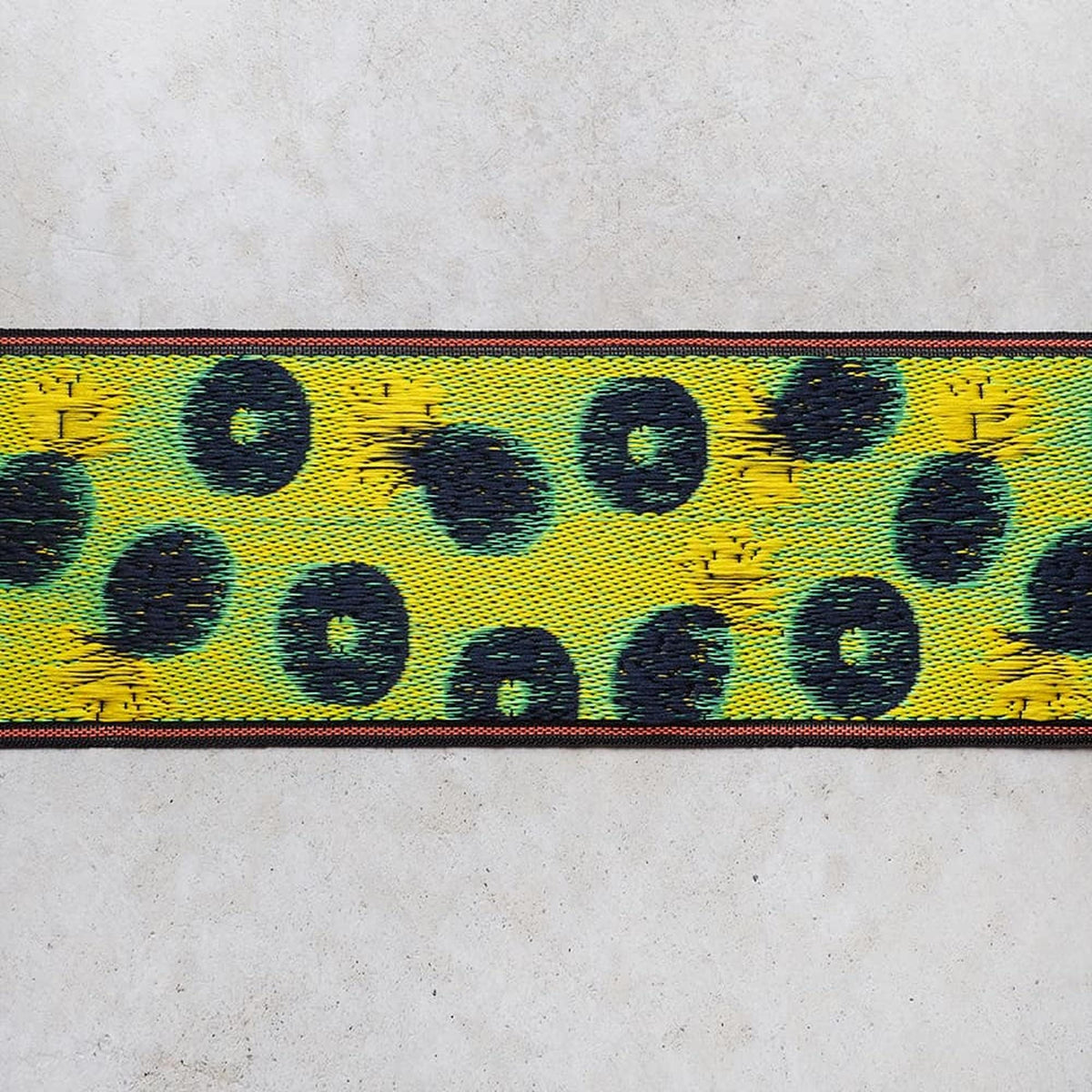 a close-up view of a colorful, textured fabric with a repeating pattern of yellow and black circles.