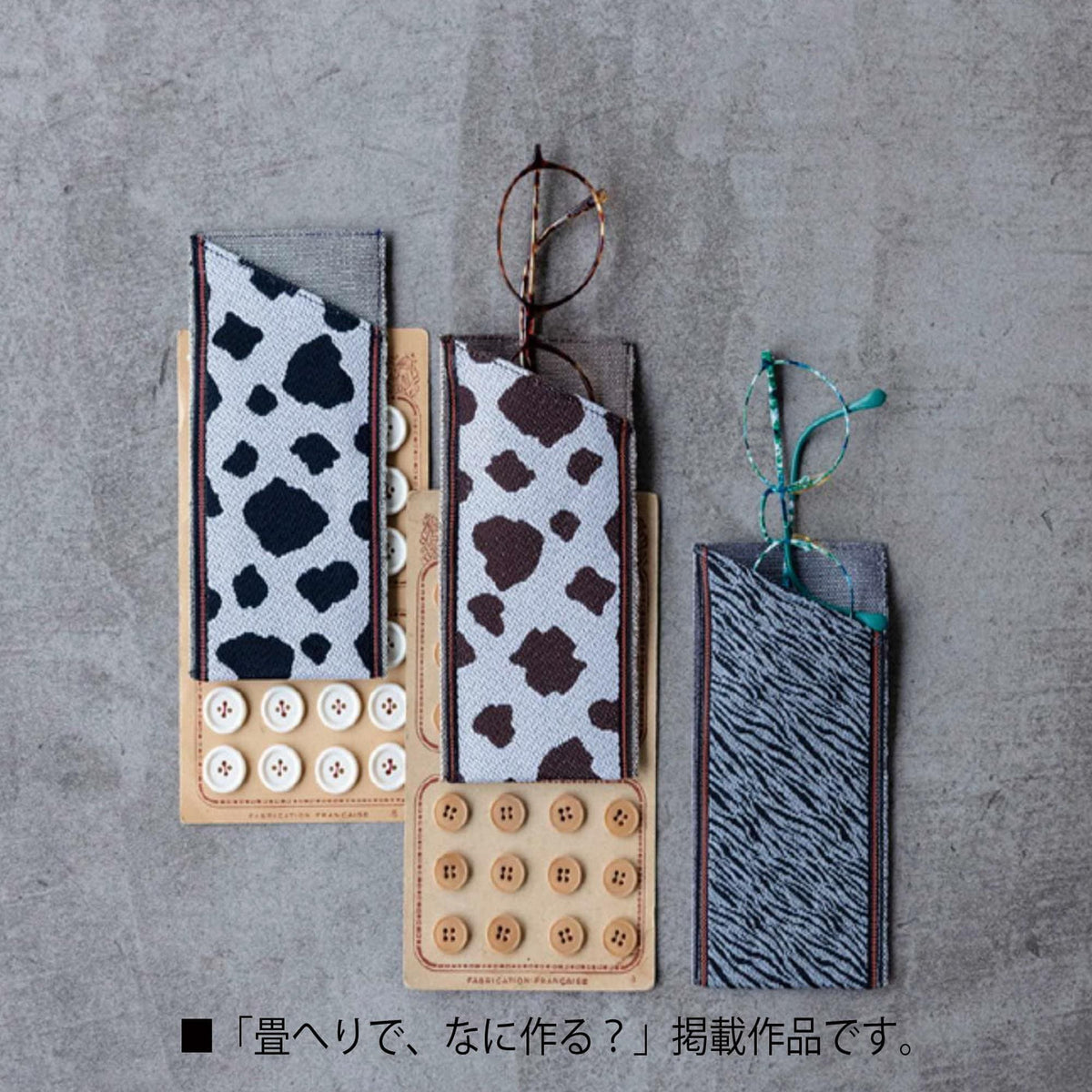 three eyeglasses cases with different patterns, including a cow print, a zebra print, and a plain white case.