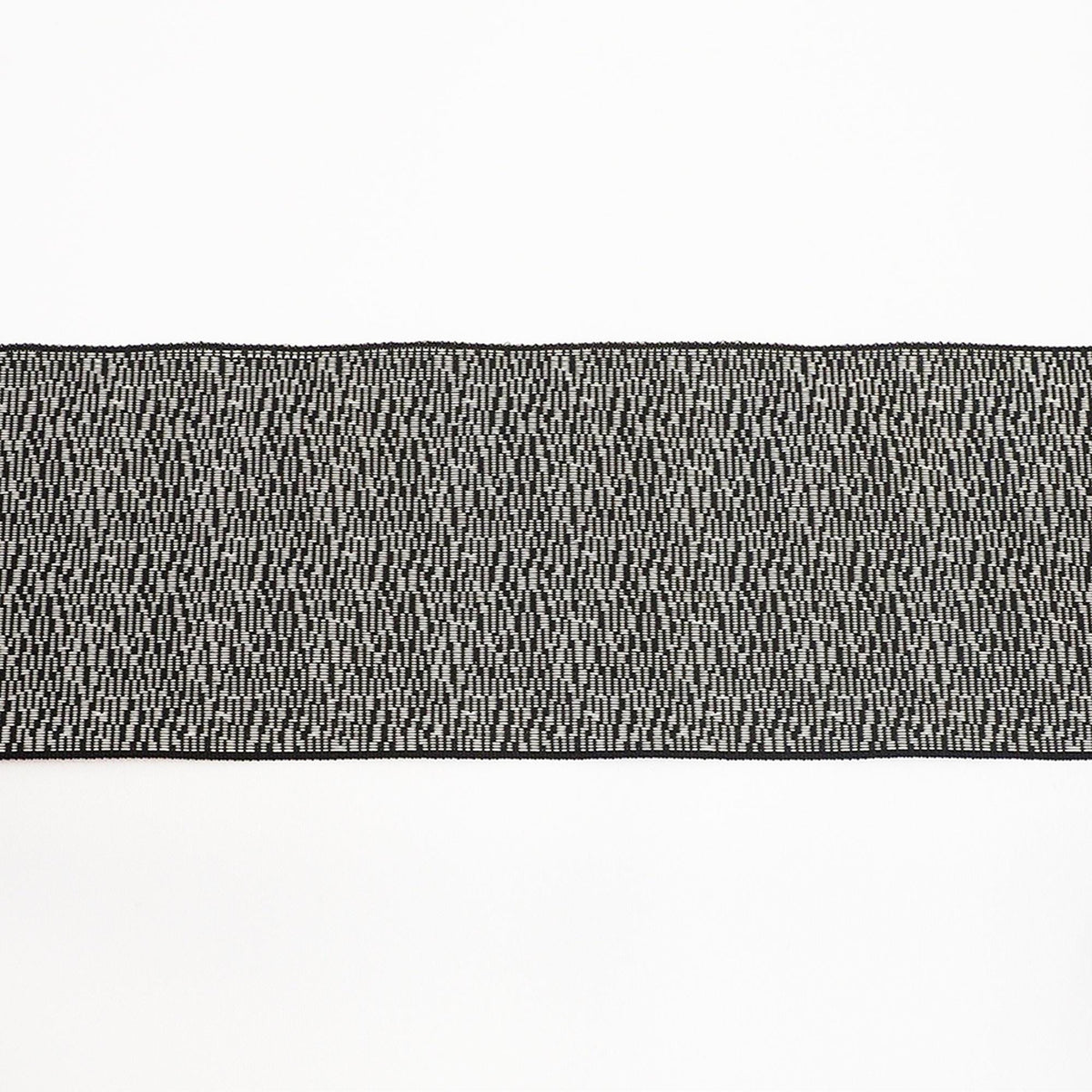 a close-up view of a black and white striped fabric or textile, with a repeating pattern of small black dots or lines creating a textured appearance.