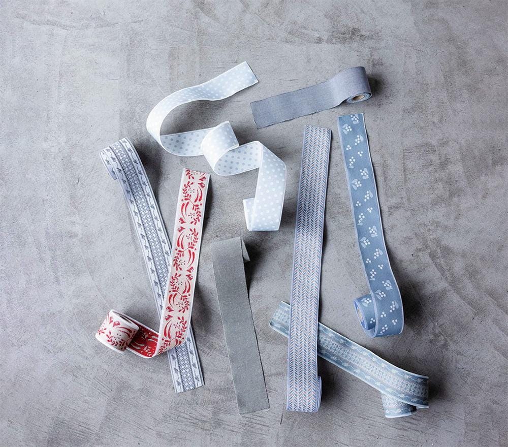a collection of various colored and patterned ribbons and fabric strips arranged on a gray surface.