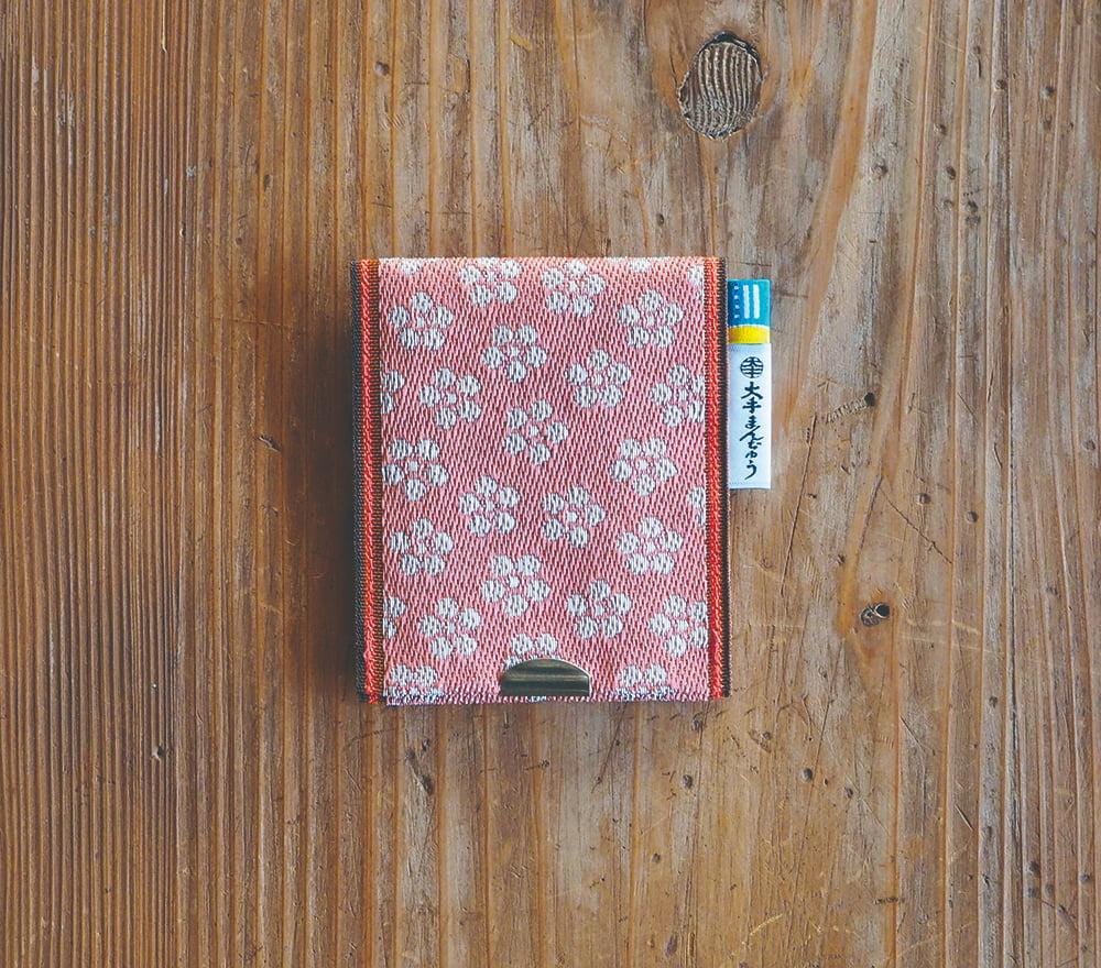 A red and white patterned wallet is placed on a wooden surface.