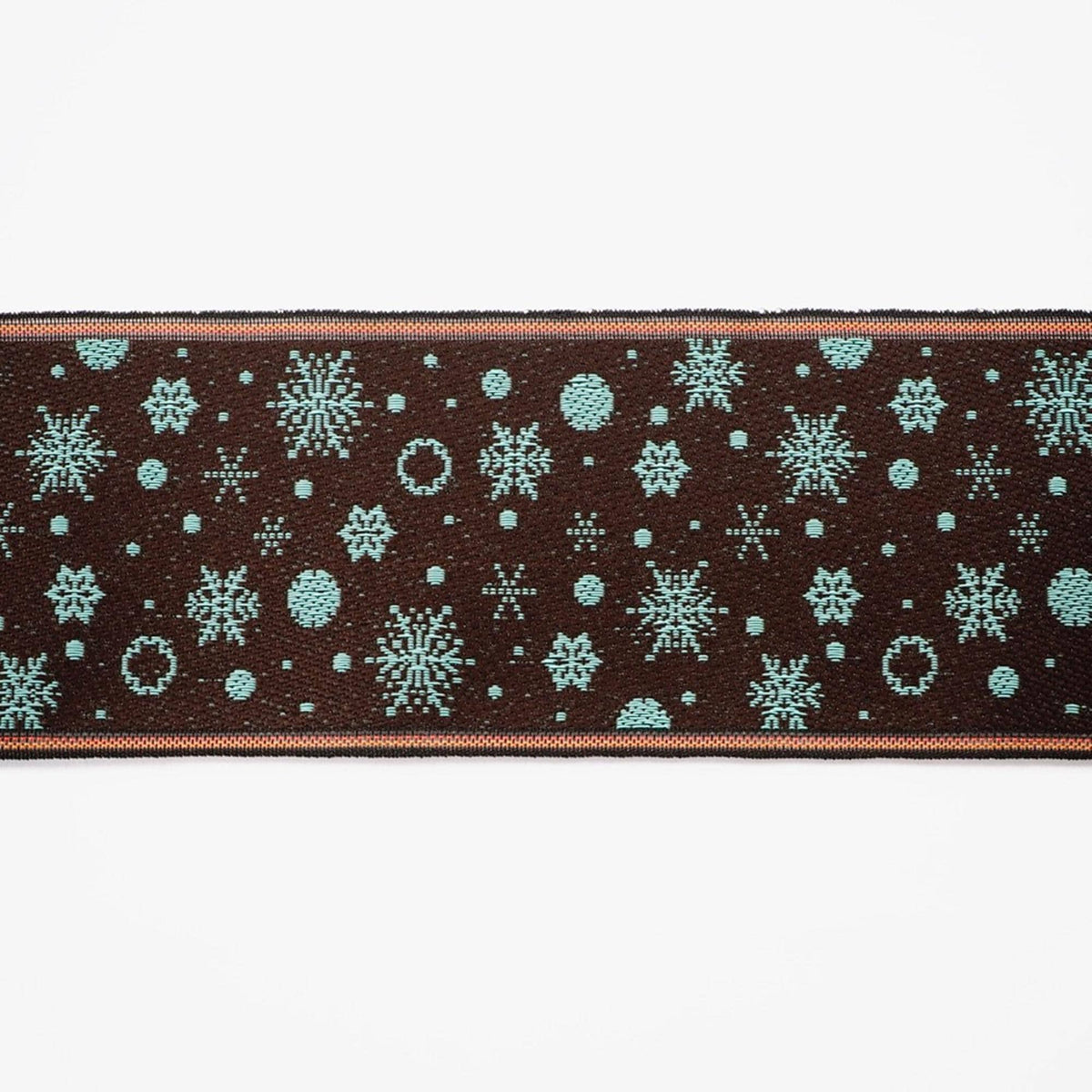 a close-up view of a dark brown fabric adorned with a repeating pattern of blue snowflakes and small circles.
