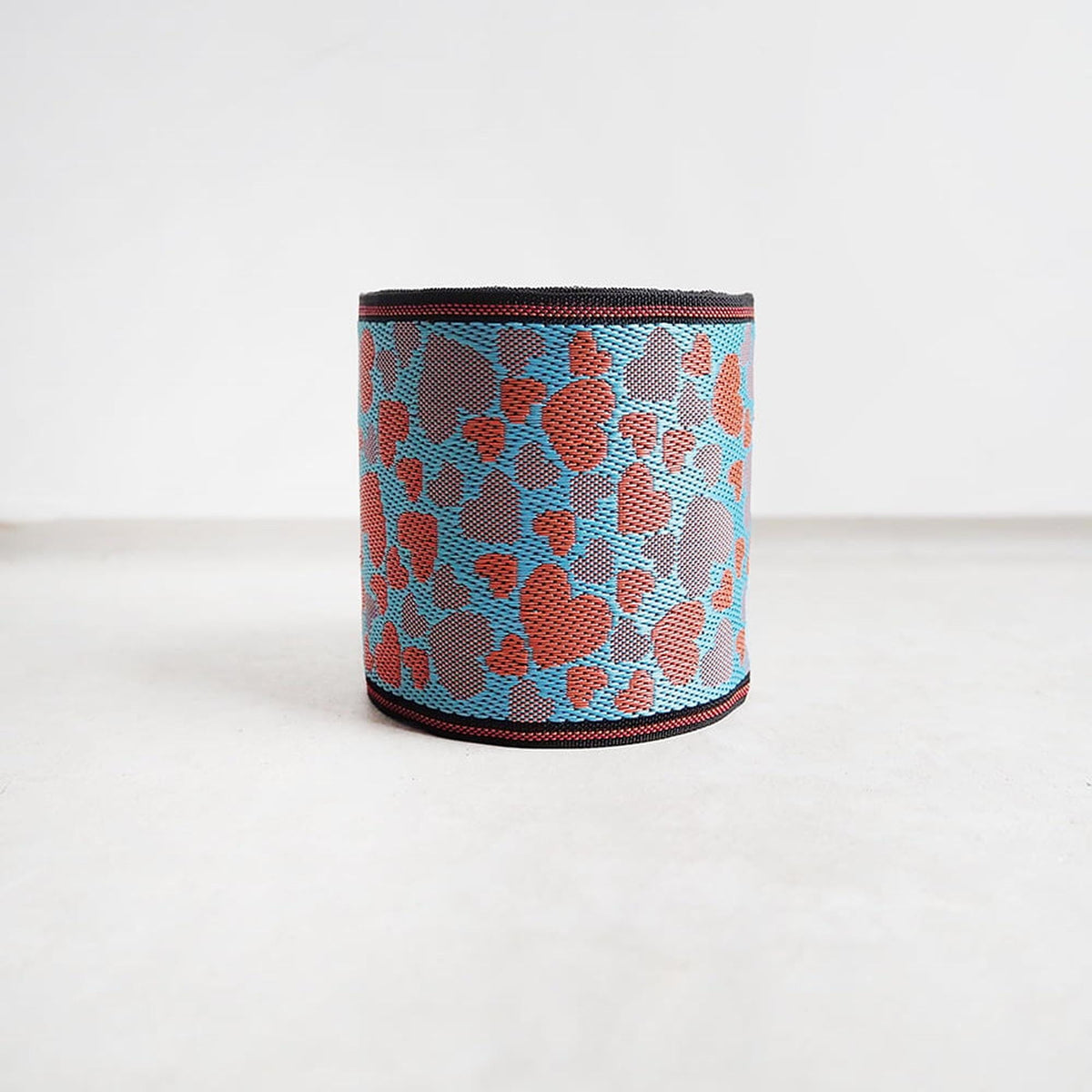 A blue and orange patterned object, possibly a piece of clothing or accessory, is standing alone on a white surface against a plain background.