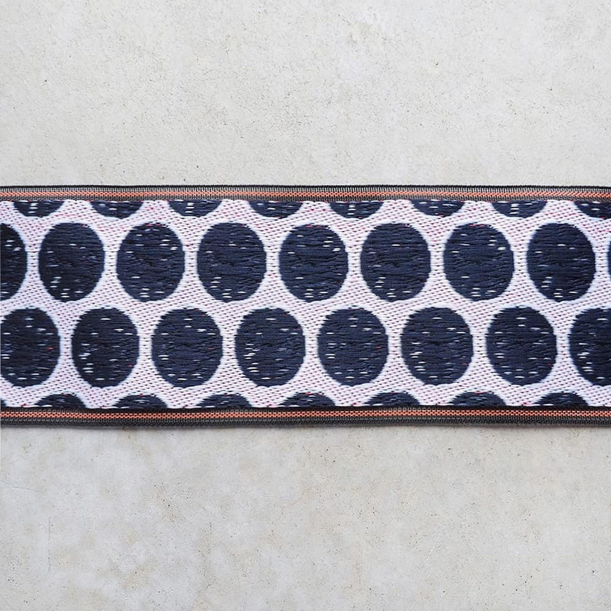 a close-up view of a fabric with a repeating pattern of black and white circles on a white background.
