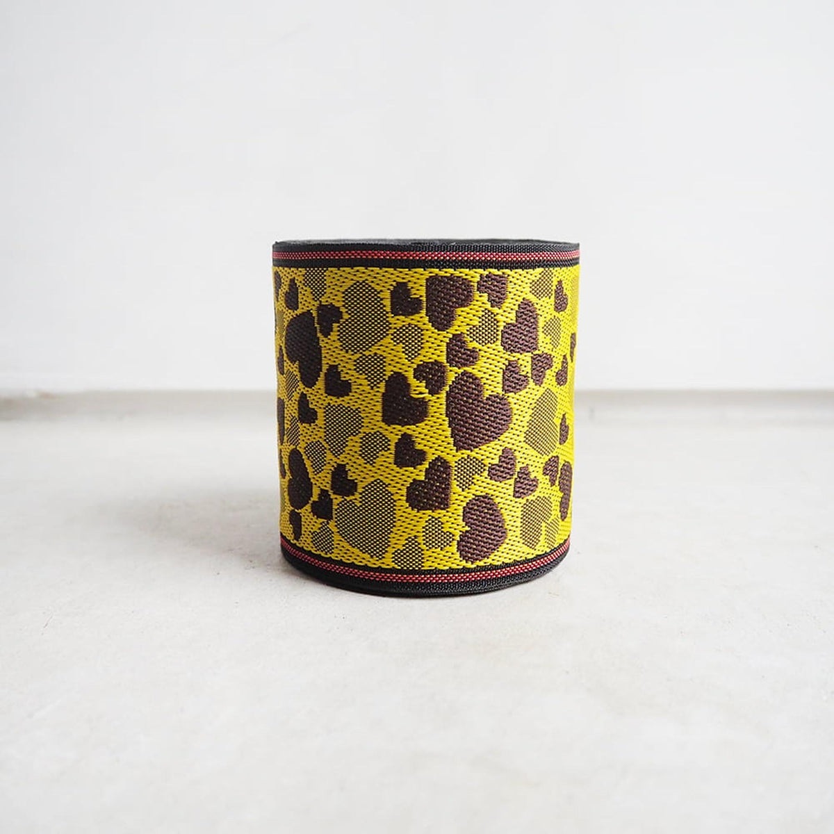 A yellow and black patterned object, possibly a container or accessory, is sitting on a white surface against a plain background.