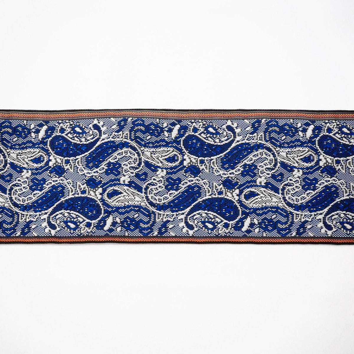 a close-up view of a decorative textile with a repeating pattern of blue and white paisley designs.