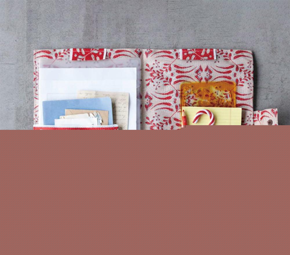 a red and white patterned pocket organizer with various items stored in it, including a candy cane, a yellow sticky note, and some papers.