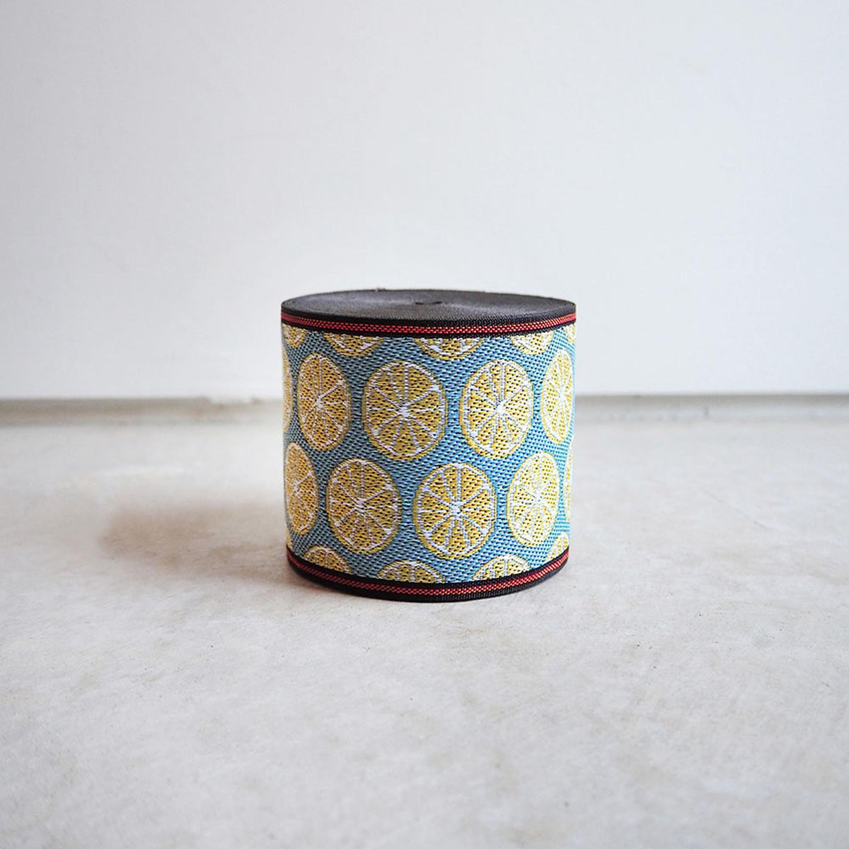 A round object with a pattern of yellow and blue circles on a black background, sitting on a white surface.