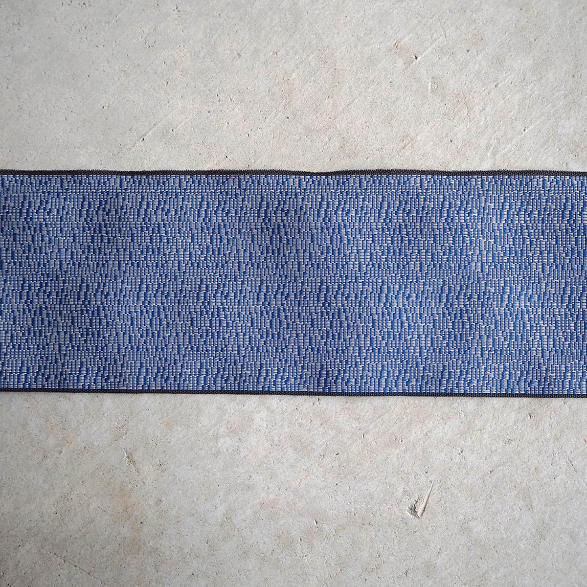 a close-up view of a blue and white striped fabric or textile, with a textured surface beneath it.