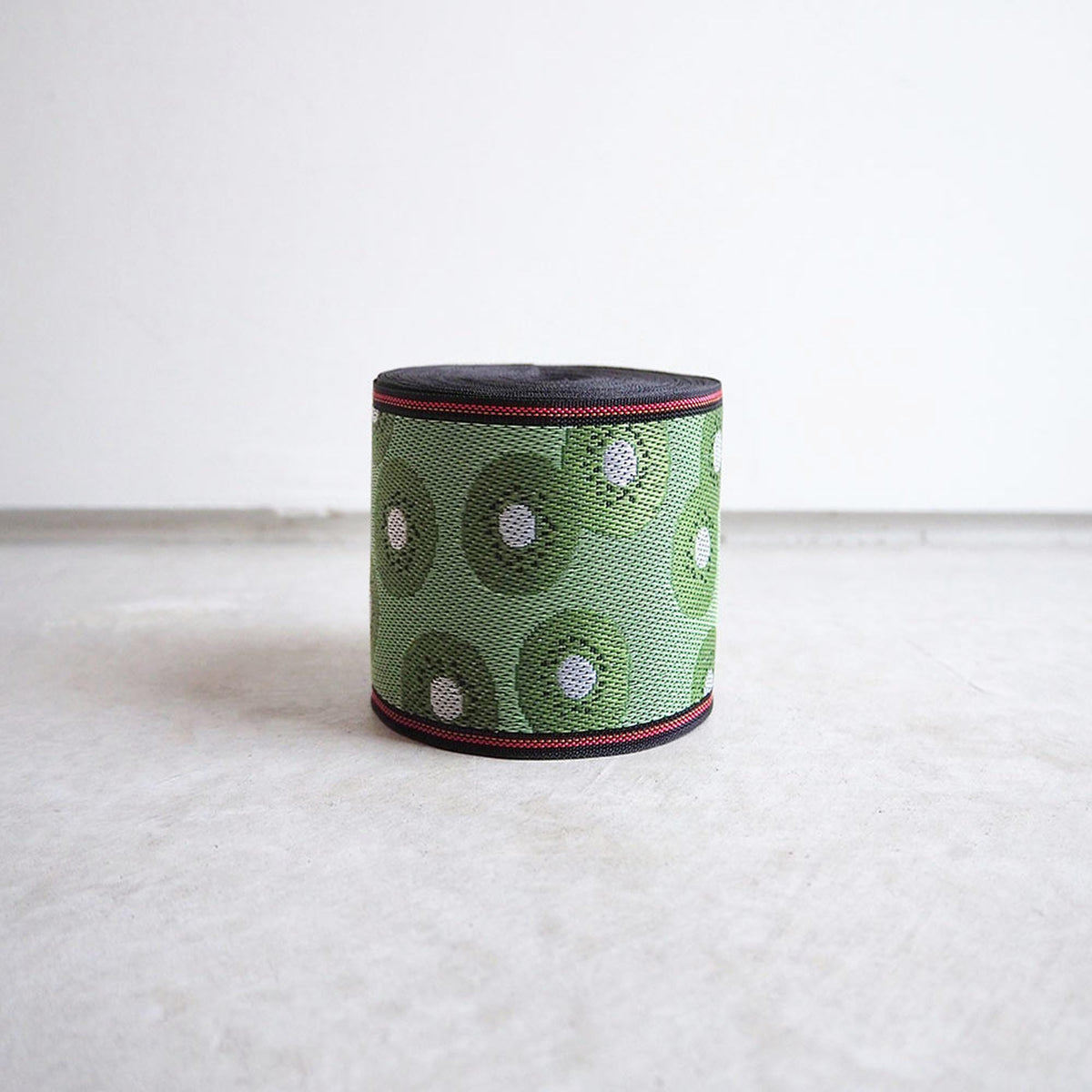A green and black circular object with a red border, sitting on a white surface.