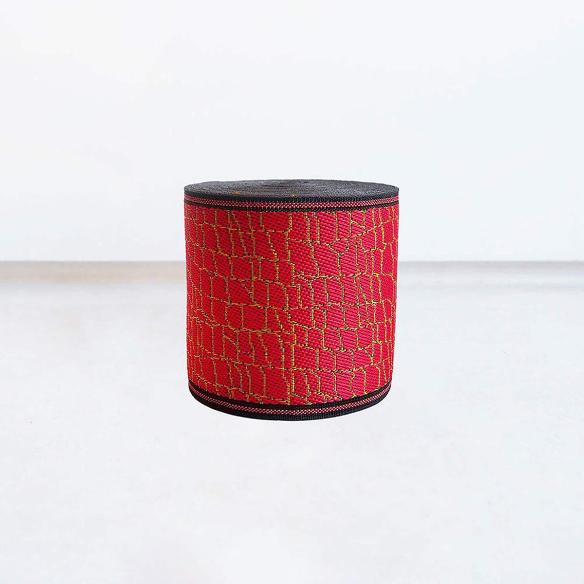 A red and black patterned object, possibly a piece of clothing or a decorative item, is centered in the image against a plain white background.