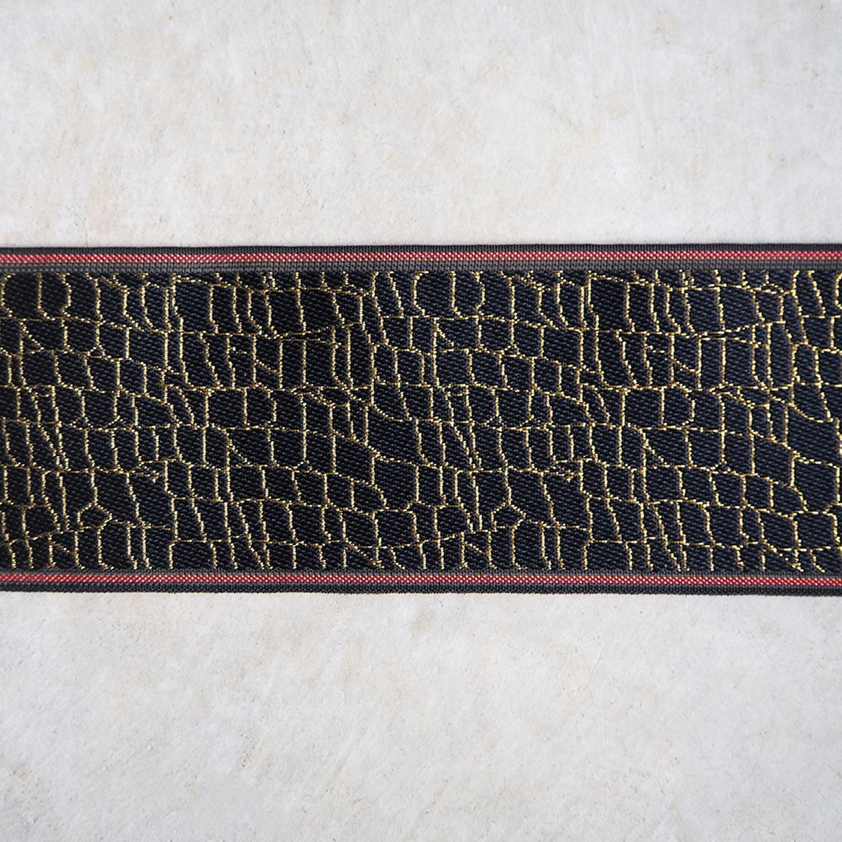 a close-up view of a black and red striped fabric or ribbon with a textured pattern.